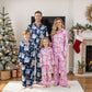 Family of four wearing matching pajamas in a festive living room with Christmas decorations.